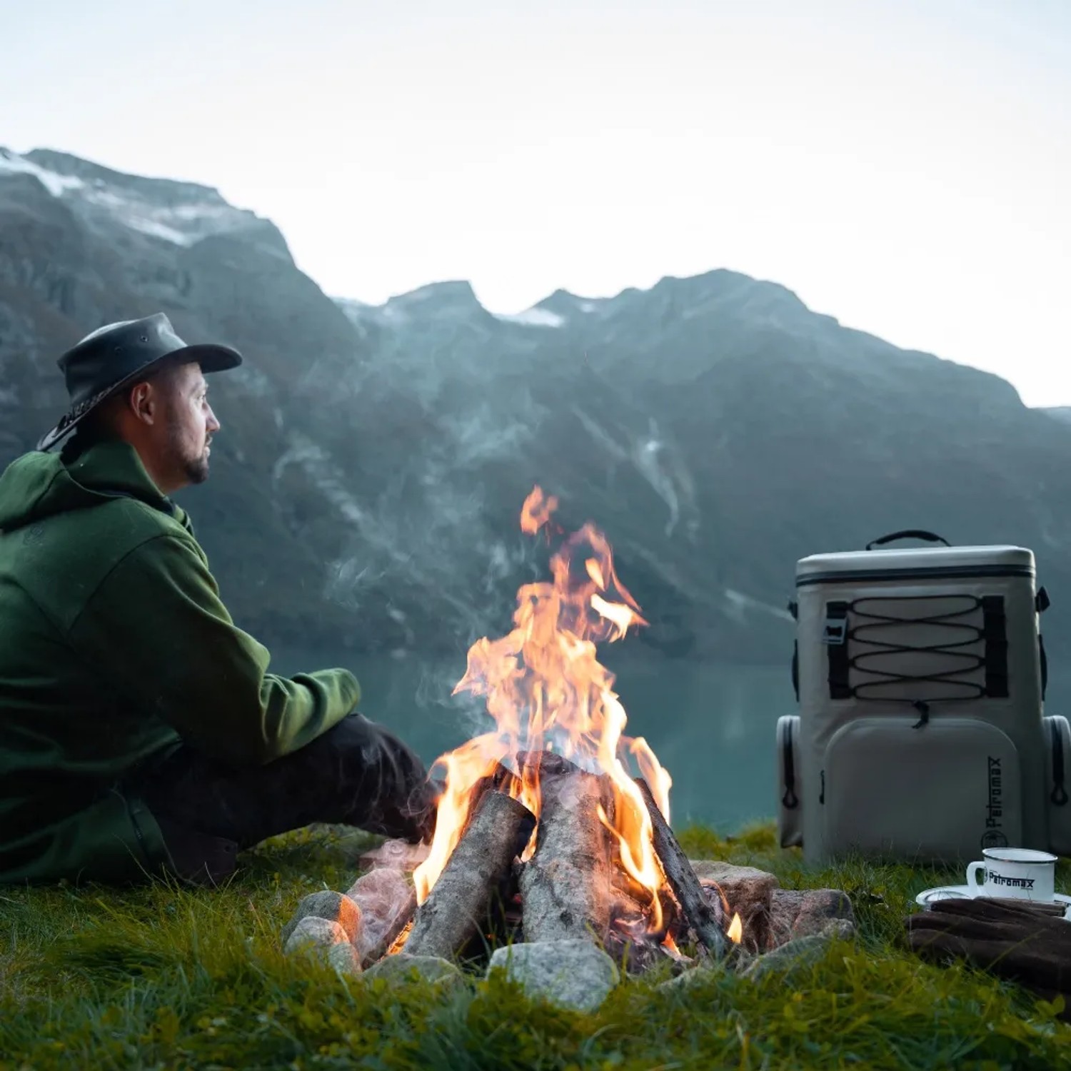 Petromax Kühlrucksack (7 l, Olive) am Lagerfeuer in der Natur. Ideal für Outdoor-Abenteuer.