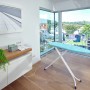 Leifheit Bügeltisch AirBoard Compact M Plus mit blauem Bezug und Bügeleisenablage im Raum.