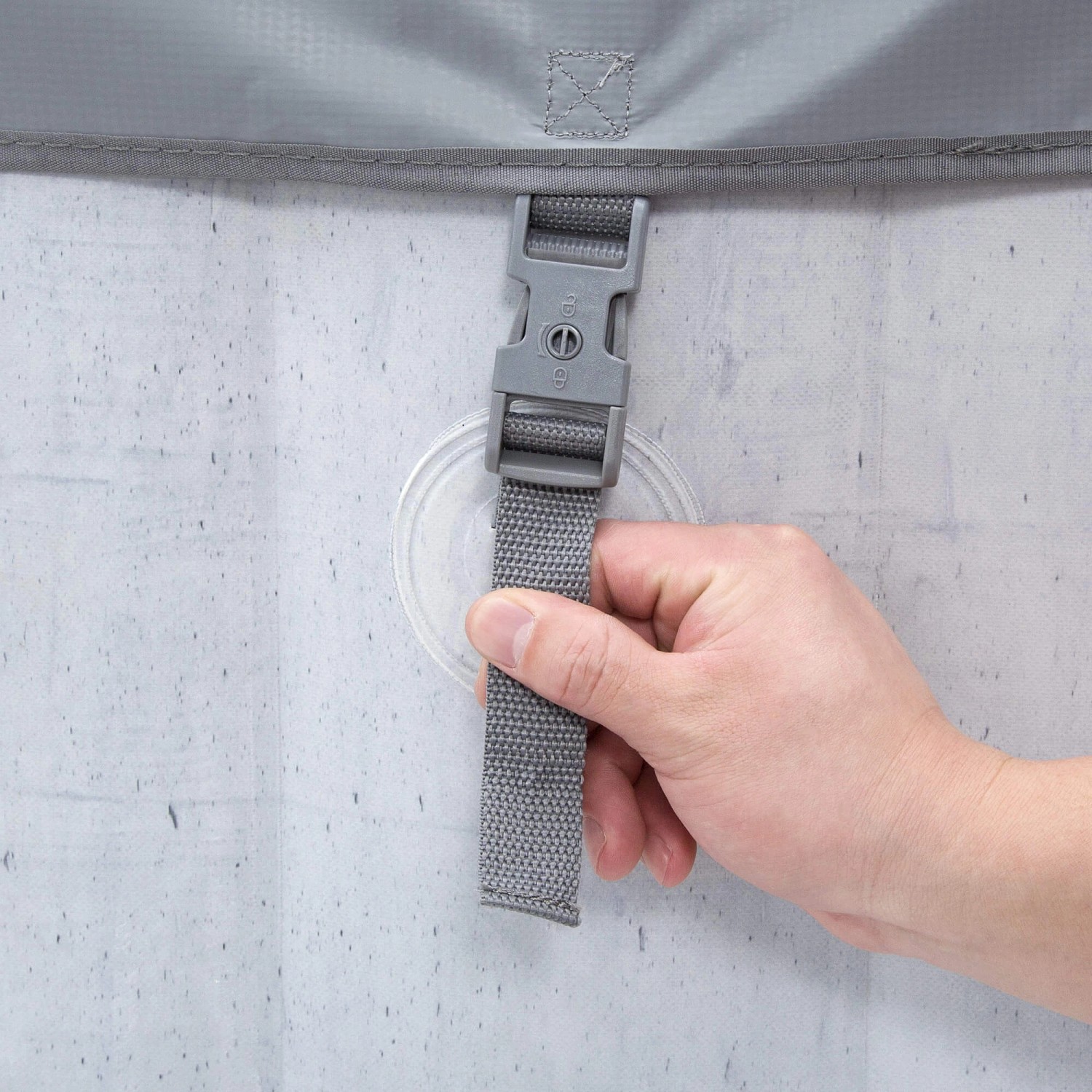 Detailaufnahme: Graue Abdeckung des Home Deluxe Whirlpools mit Verschluss und Hand.