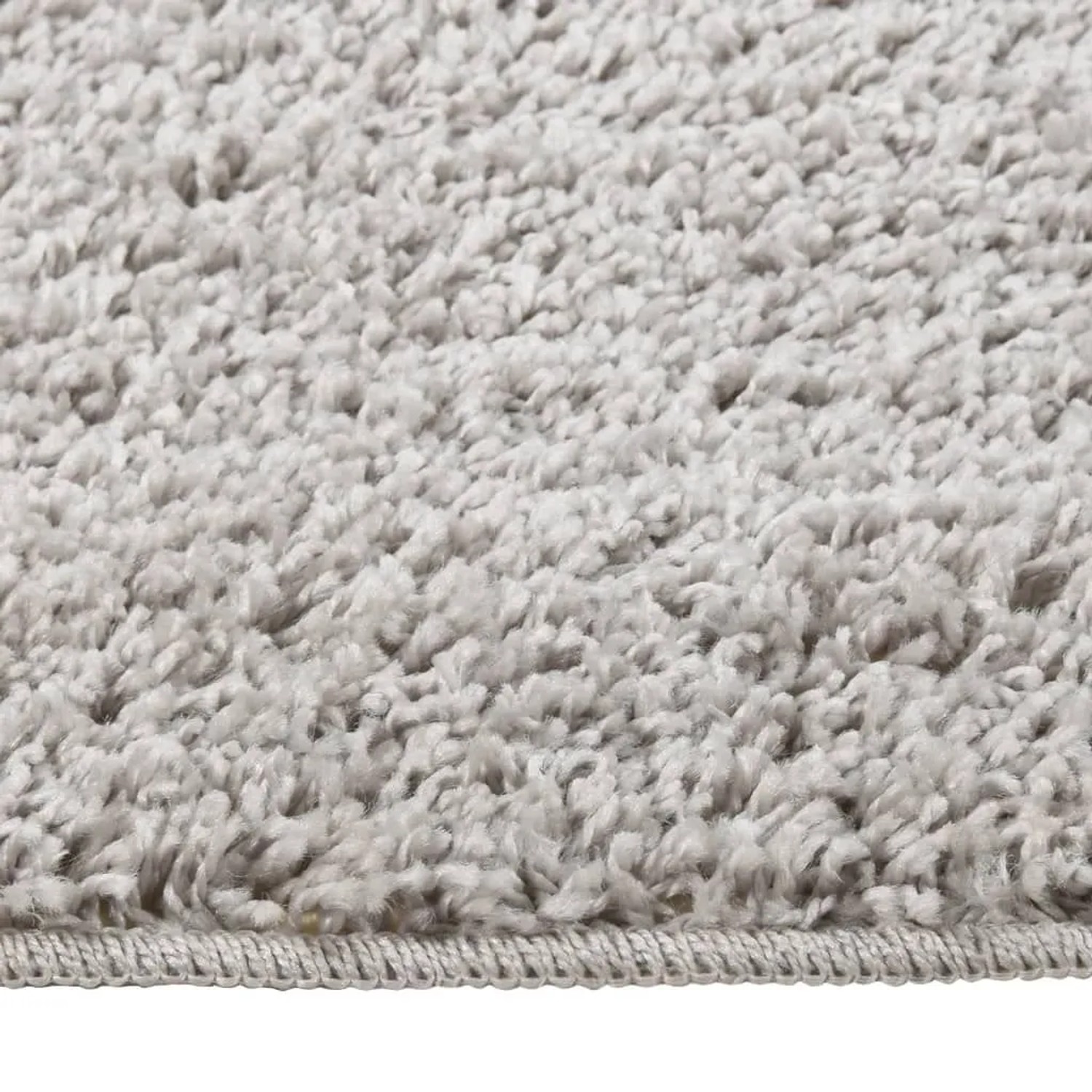 Detailansicht eines hellgrauen Shaggy-Teppichs (80x150 cm) mit rutschfester Unterseite.
