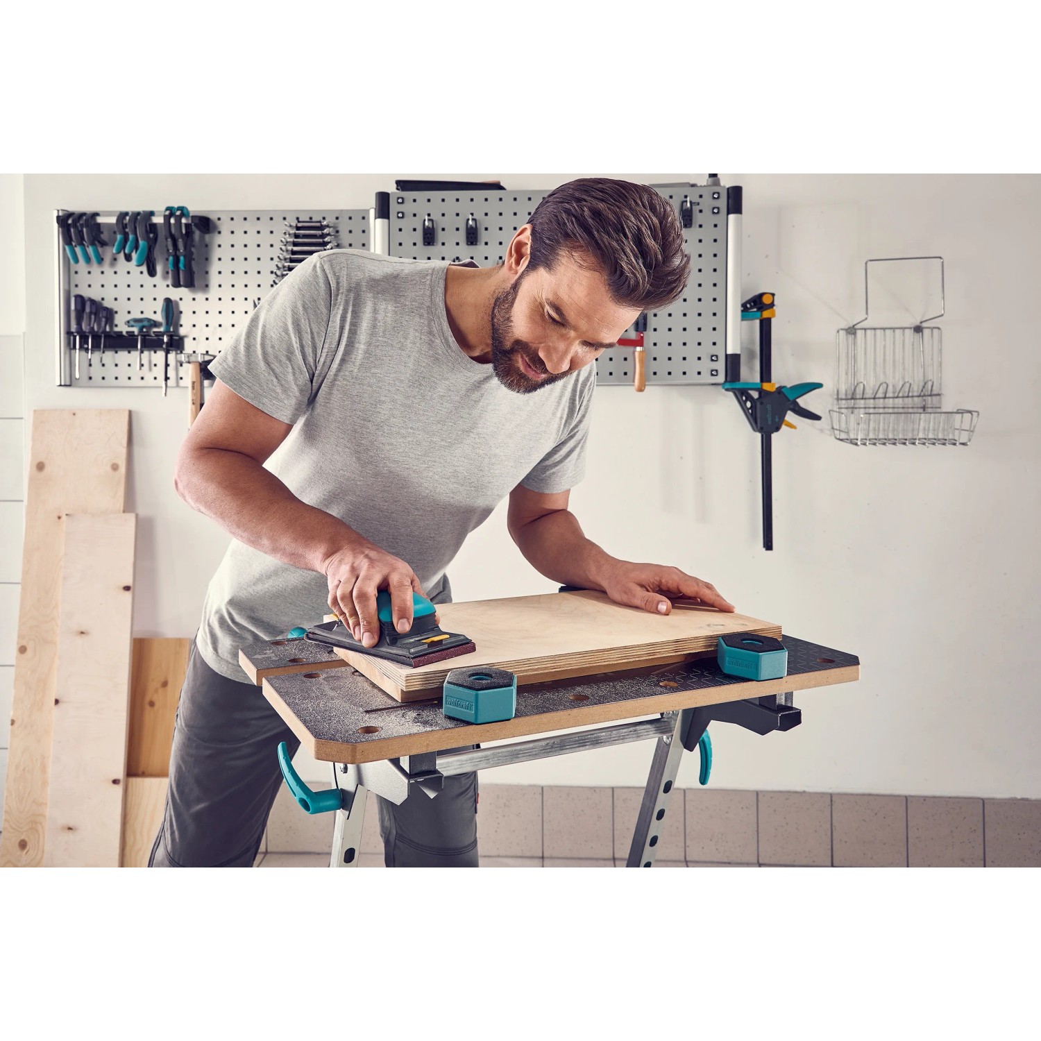 Mann schleift Holz auf Werkbank mit wolfcraft Werkstückauflagen-Set für sicheren Halt.