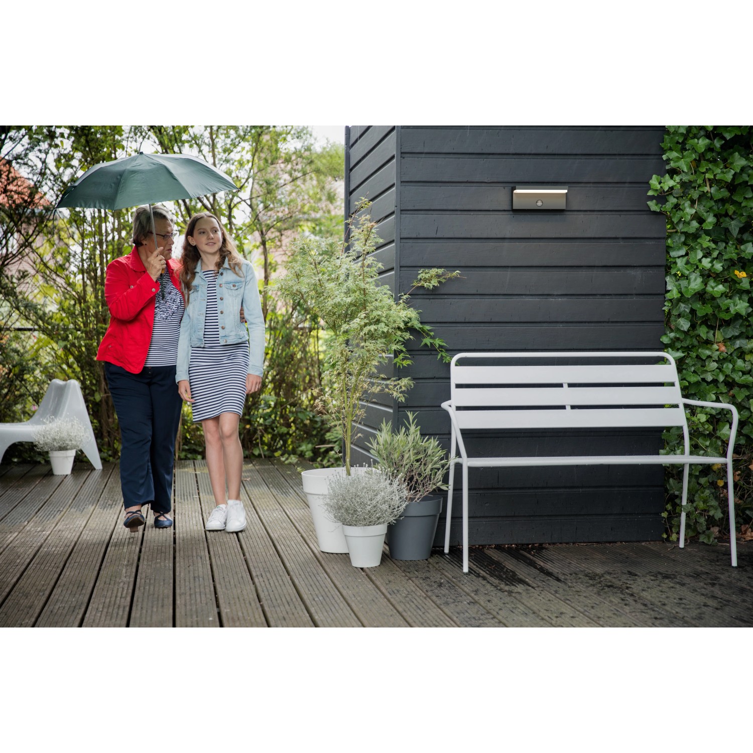 Philips myGarden Bustan LED-Außenwandleuchte mit Bewegungsmelder an dunkler Holzwand.