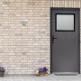 Anthrazitfarbene Stahl-Nebeneingangstür mit Fenster, nach innen öffnend, links angeschlagen.