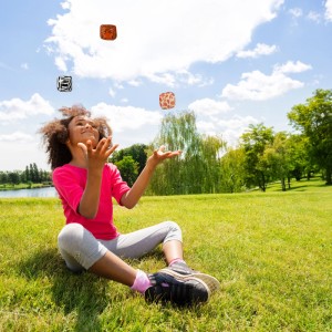 Mädchen jongliert mit bunten Jonglierbällen (24er Set) im Park. Spiel & Spaß für Kinder und Erwachsene.