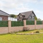 Diephaus Mauer Canta Normalstein Sandstein als Garteneinfassung mit grüner Hecke und Wohnhäusern im Hintergrund.