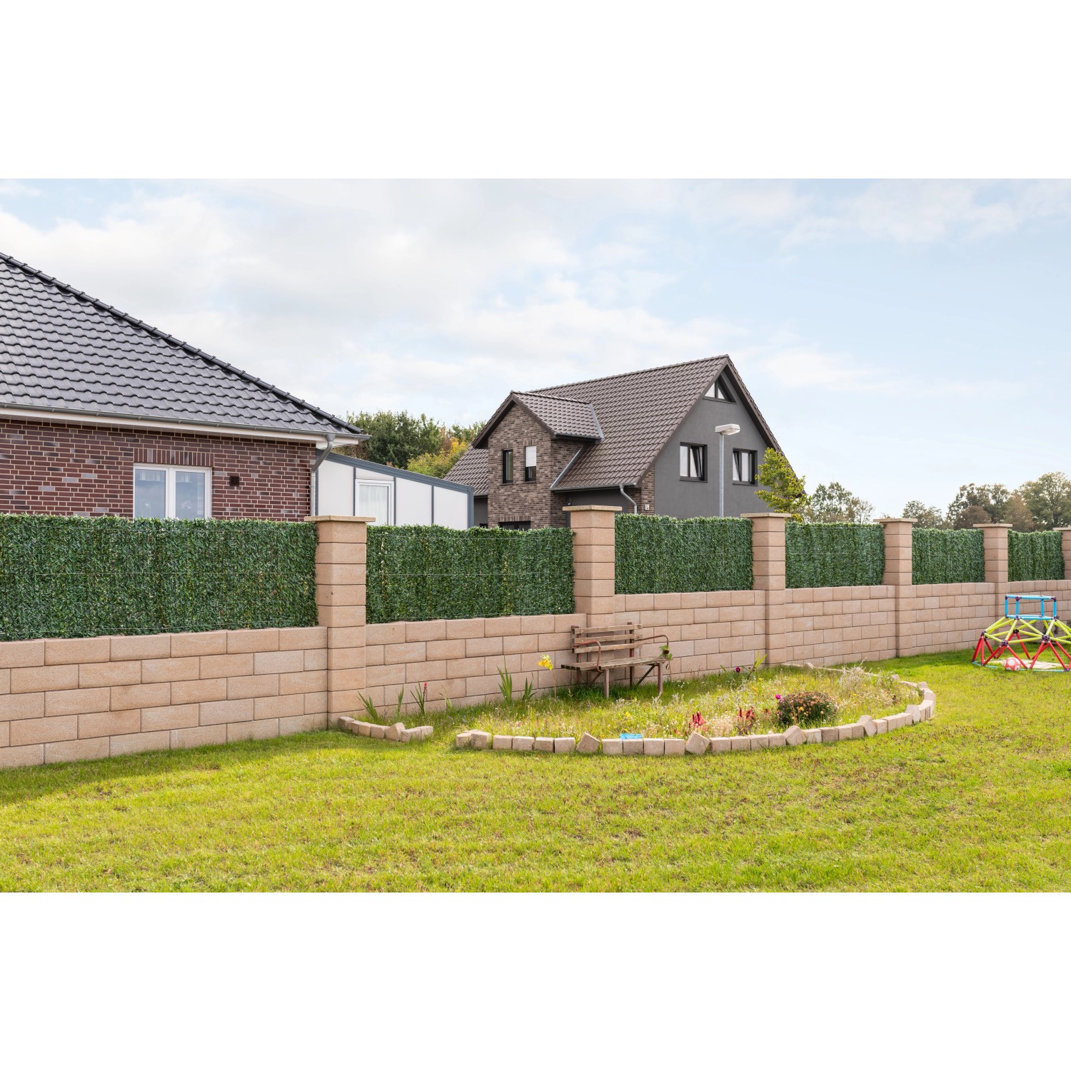 Diephaus Mauer Canta Normalstein Sandstein als Garteneinfassung mit grüner Hecke und Wohnhäusern im Hintergrund.