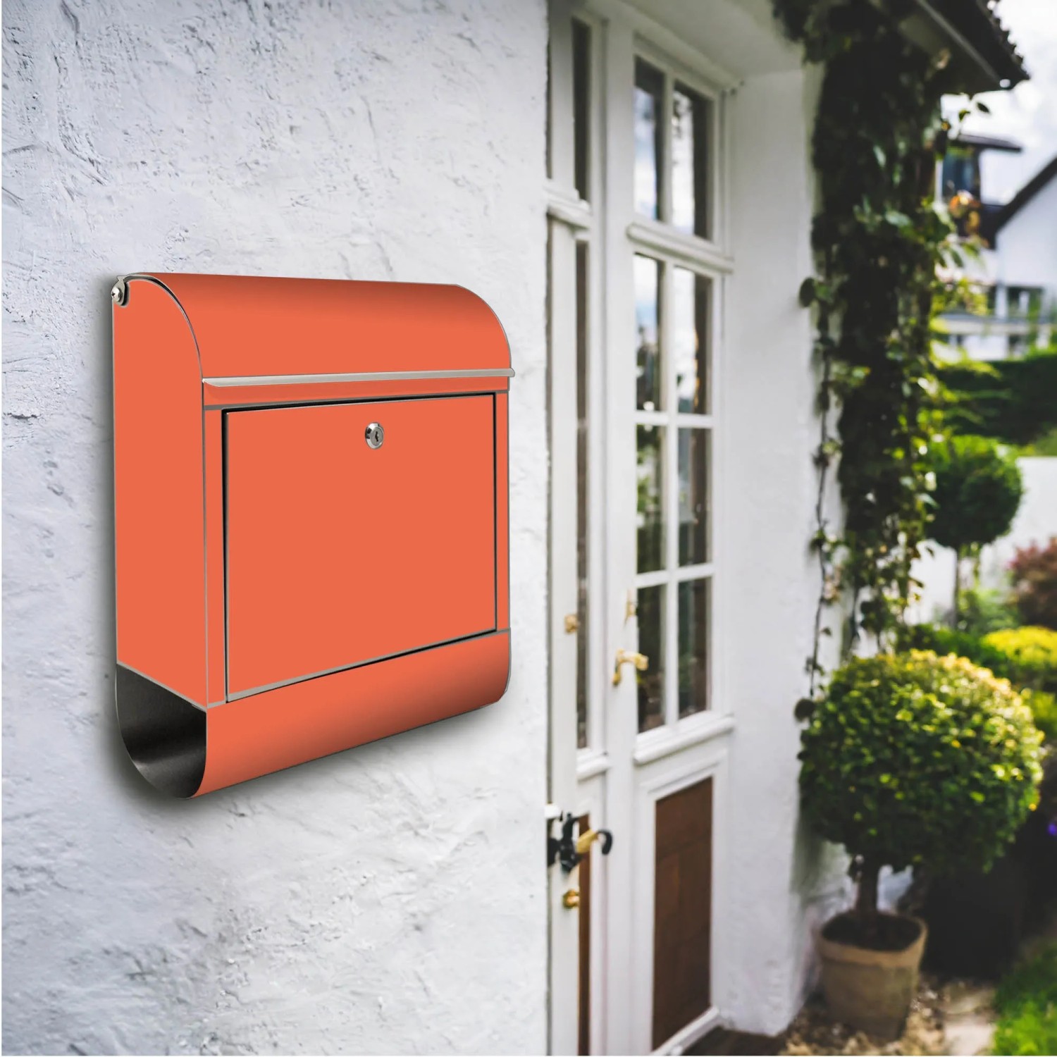 Orangefarbener Banjado Edelstahl Briefkasten mit Zeitungsfach an weißer Hauswand.
