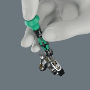 Hand mit grün-schwarzem Wera Kraftform Micro Schraubendreher an Elektronik. Präzises Werkzeugset für Feinmechanik.