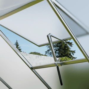 Geöffnetes Dachfenster mit automatischem Fensteröffner im Gewächshaus. Belüftung und Temperaturregelung.