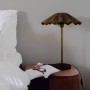 PR Home Aira Tischleuchte mit plissiertem Schirm in Messing-Optik auf Nachttisch.