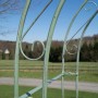 Antik-grüner Metall-Rosenbogen mit dekorativen Rankgitter-Verzierungen. Detailansicht der Rankhilfe im Garten.