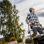 Mann mit 3M Peltor Kapselgehörschutz X2A beim Rasenmähen im Garten.