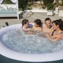 Vier Personen genießen den Bestway Whirlpool Miami AirJet im Garten. Dunkelgrüner, aufblasbarer 6-Personen-Whirlpool mit Sprudel.