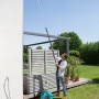 Mann reinigt Dachrinne mit Gardena combisystem Dachrinnenreiniger und Teleskopstiel im Garten.
