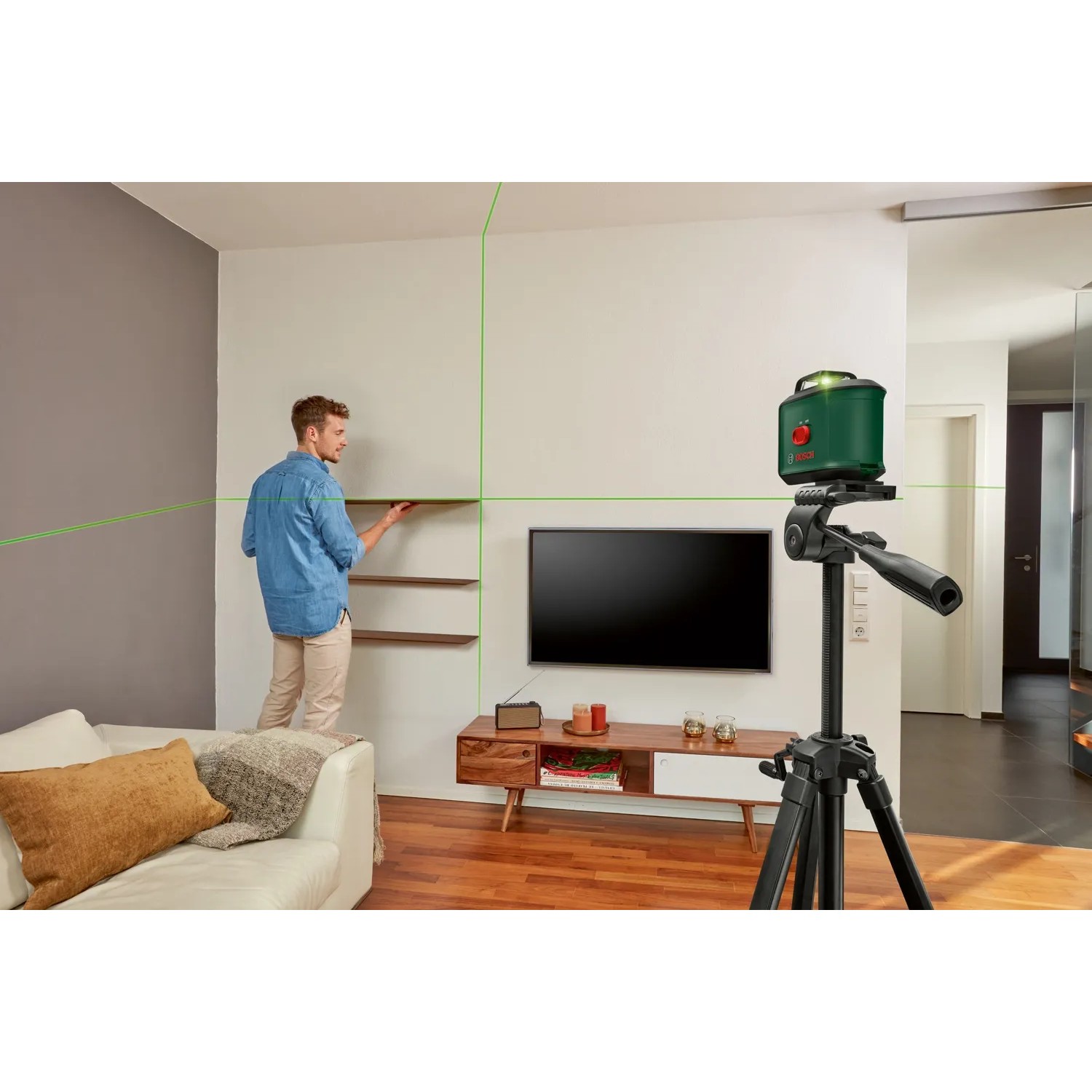 Bosch UniversalLevel 360 Kreuzlinienlaser im Einsatz mit Stativ und grünen Laserlinien beim Regale ausrichten.