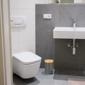 Grauer Relaxdays Mülleimer mit Bambusdeckel und Pedal im Badezimmer.