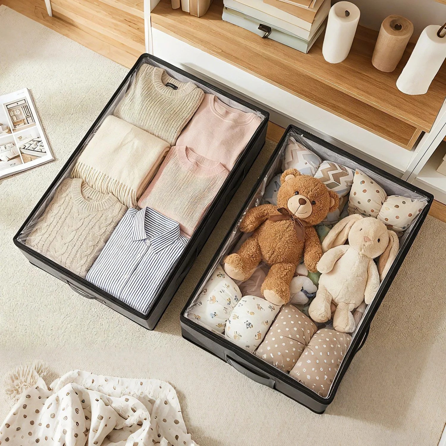 Zwei graue Unterbett-Aufbewahrungsboxen mit transparentem Deckel, gefüllt mit Kleidung und Spielzeug. Textil-Aufbewahrung.