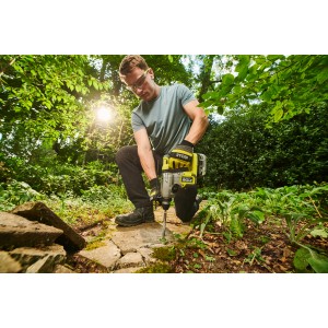 Mann arbeitet mit Ryobi Akku-SDS-Bohrhammer RSDS18BL-0 im Garten.