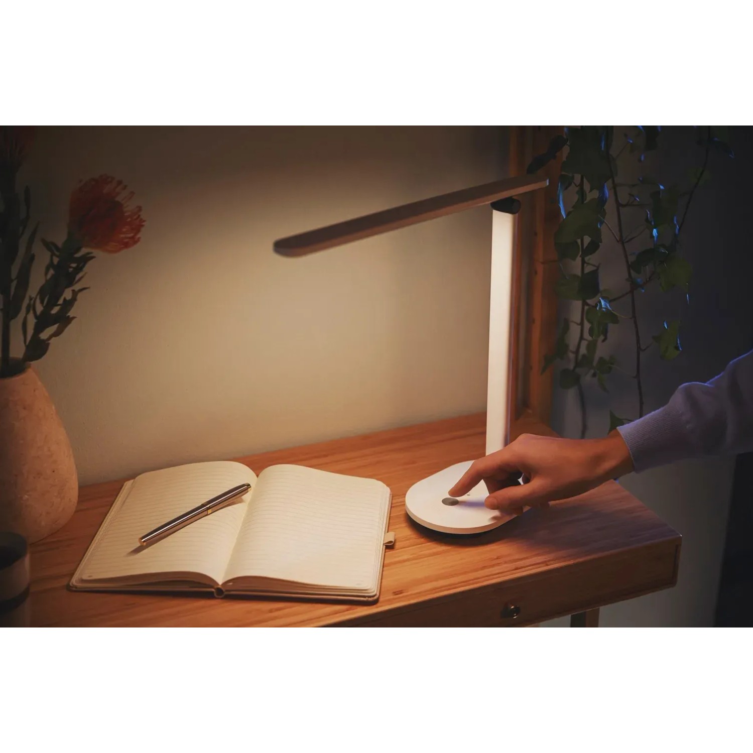 Weiße Philips LED-Tischleuchte Ivory mit Akku auf einem Schreibtisch mit Notizbuch.