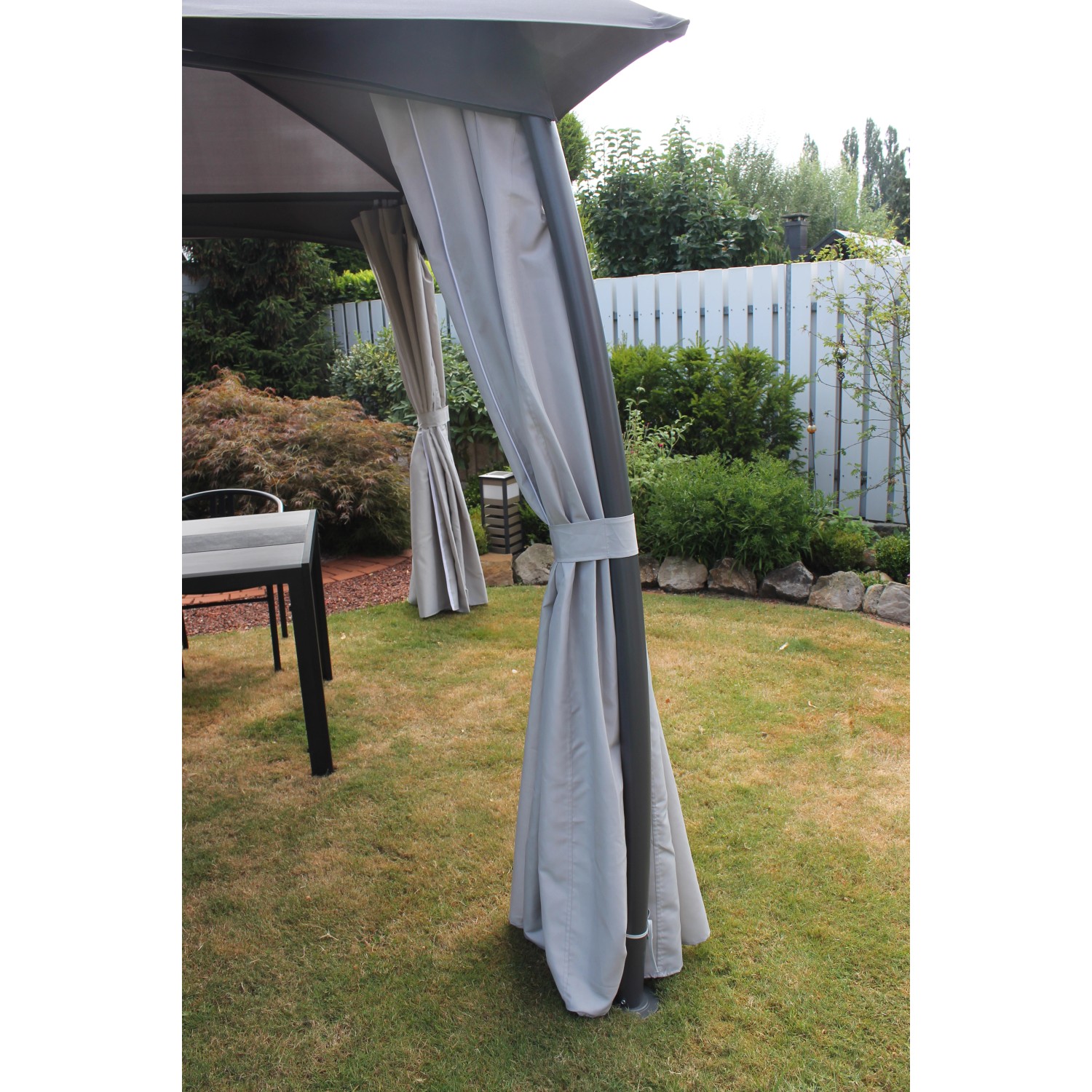 Leco Pavillon Milena mit grauen Seitenvorhängen im Garten, hoher Standfestigkeit und effektivem Sonnenschutz.