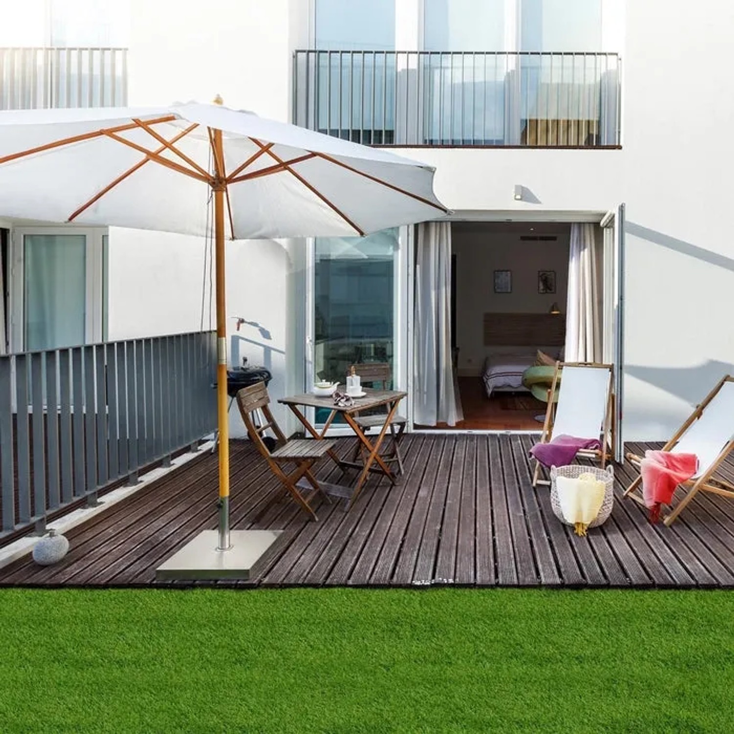 Kunstrasen Tosca 35mm auf Terrasse mit Gartenmöbeln und Sonnenschirm. Ideal für Balkon und Garten.