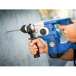 LUX Hammerbohrer Comfort SDS-Plus bohrt Loch in Betonwand mit blauem Bohrhammer.