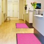 Pinke Primaflor Schmutzfangmatte Clean 60x180cm im Flur vor einem Empfangstresen.
