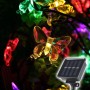 Bunte LED Solar Schmetterling-Lichterkette leuchtet im Dunkeln. Nahaufnahme der farbigen Schmetterlinge und des Solarpanels.