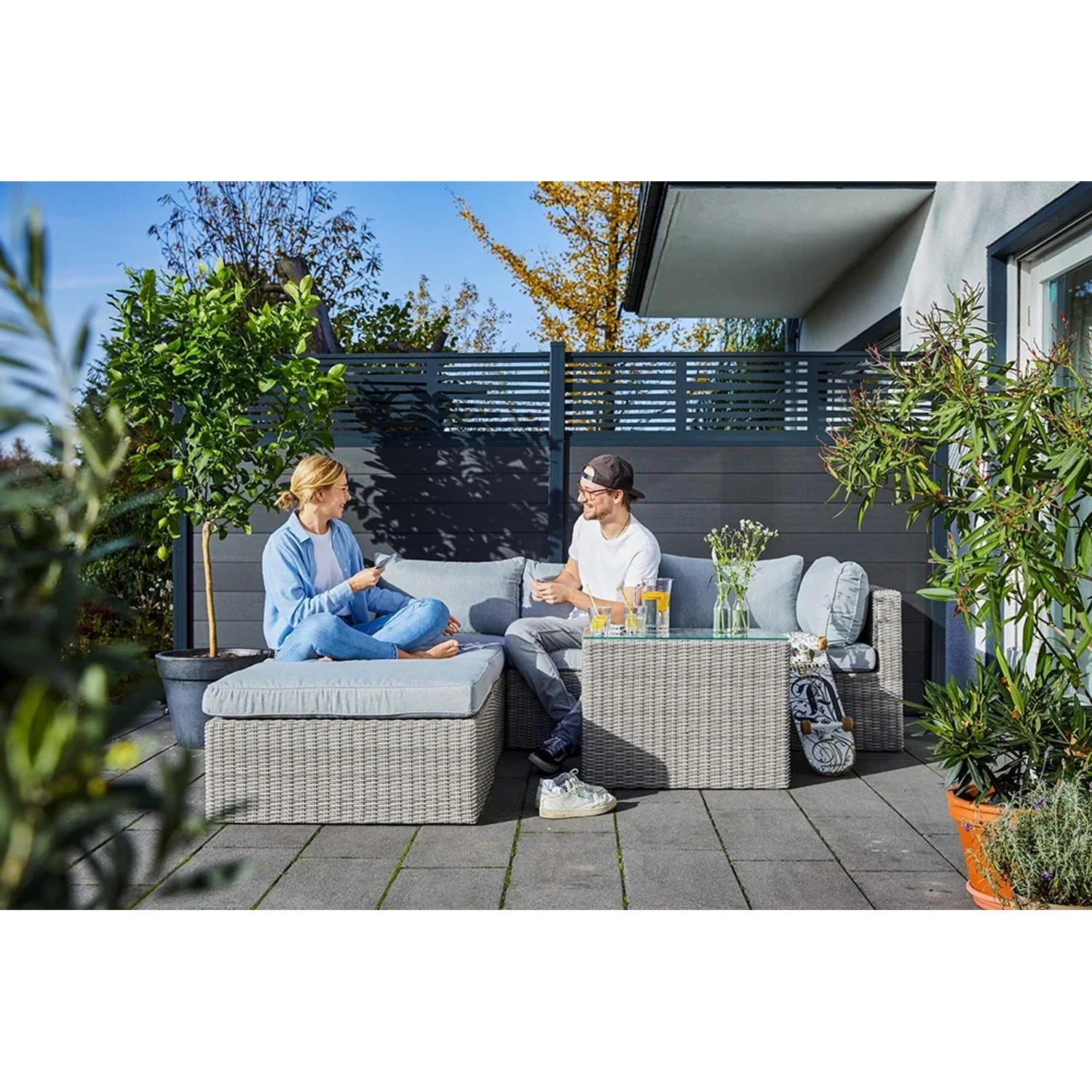 Lounge-Sessel Olea aus Polyrattan Sand mit Personen auf Terrasse. Gartenmöbel zum Entspannen.