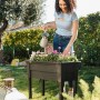 Frau gießt Blumen im anthrazitfarbenen Ondis24 Hochbeet Victoria im Garten.