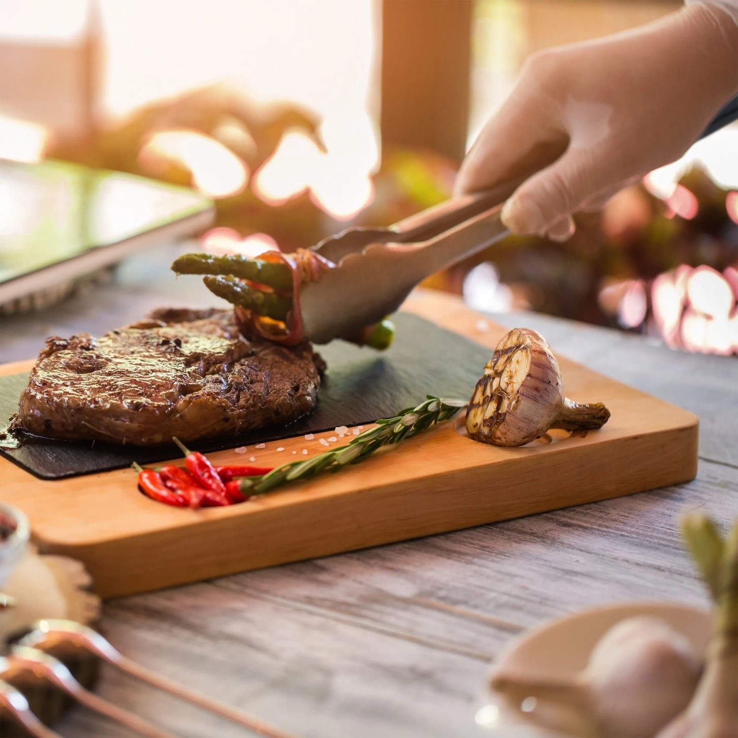 Grillzange aus Edelstahl mit Holzgriff beim Wenden von Grillgut.