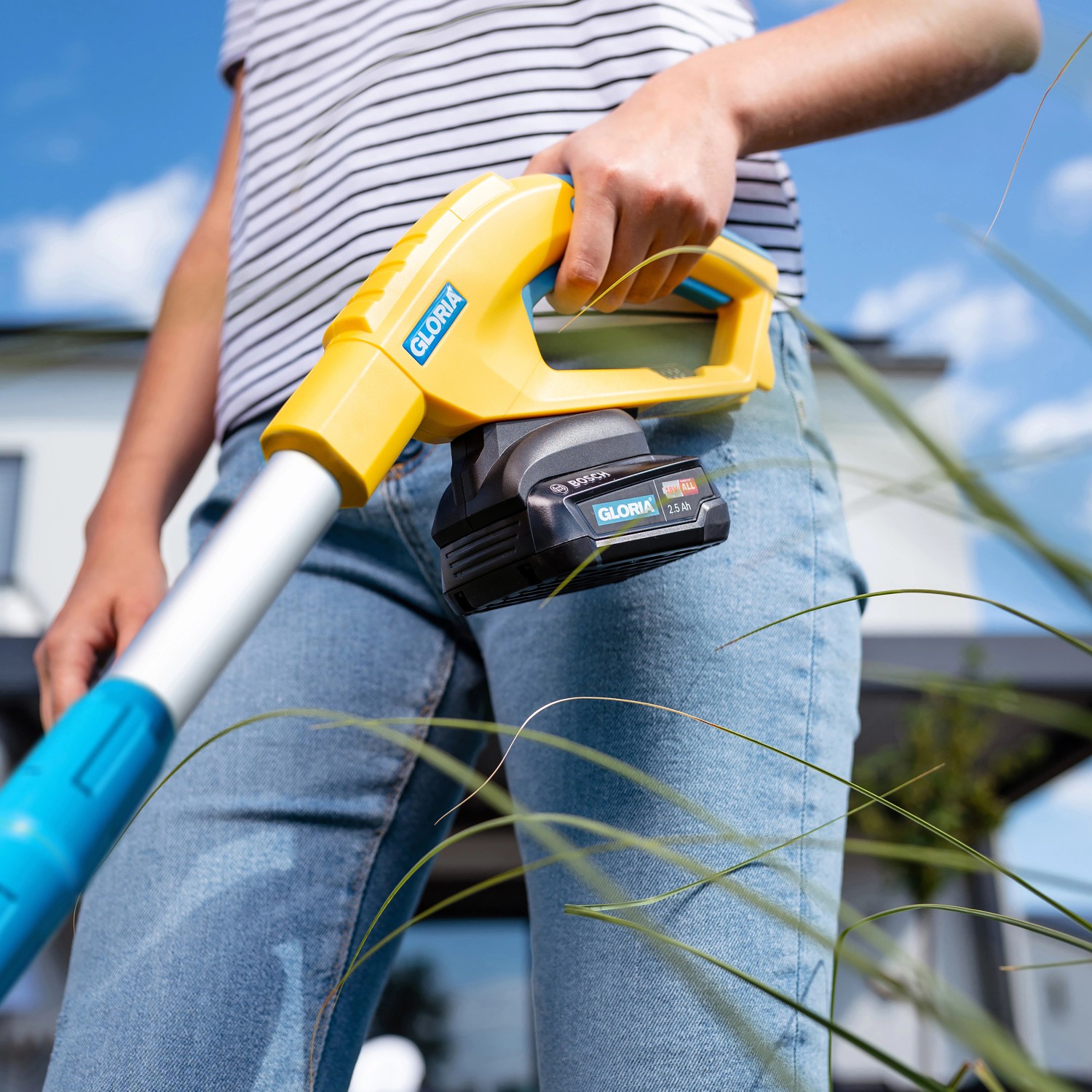 Gloria Finecut 18 V Akku-Rasentrimmer in Gelb/Blau mit Akku in der Hand einer Person.