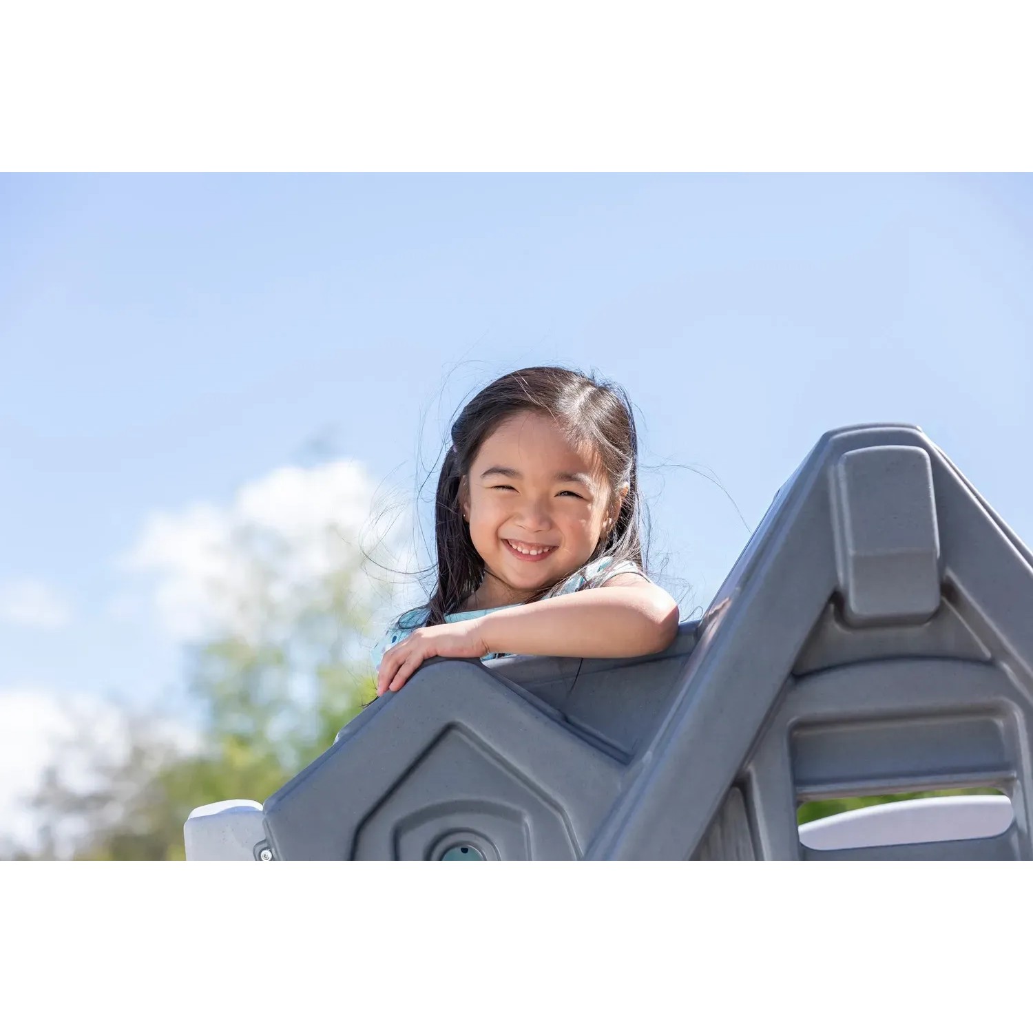 Lachendes Mädchen im Step2 Spielhaus Adventures mit Rutsche, graues 2-Etagen Spielhaus.