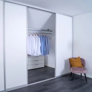 Raumhohe Schiebetür mit silbernem Profil und weißer Füllung im begehbaren Kleiderschrank.