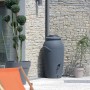 Anthrazitfarbene Waterform Regentonne Aquacan 210 l mit Deckel und zwei Anschlüssen vor Hauswand.