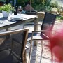 Acamp Gartenmöbel-Set Auris mit Esstisch und Stapelsesseln aus Edelstahl und dunklem Textilbezug.