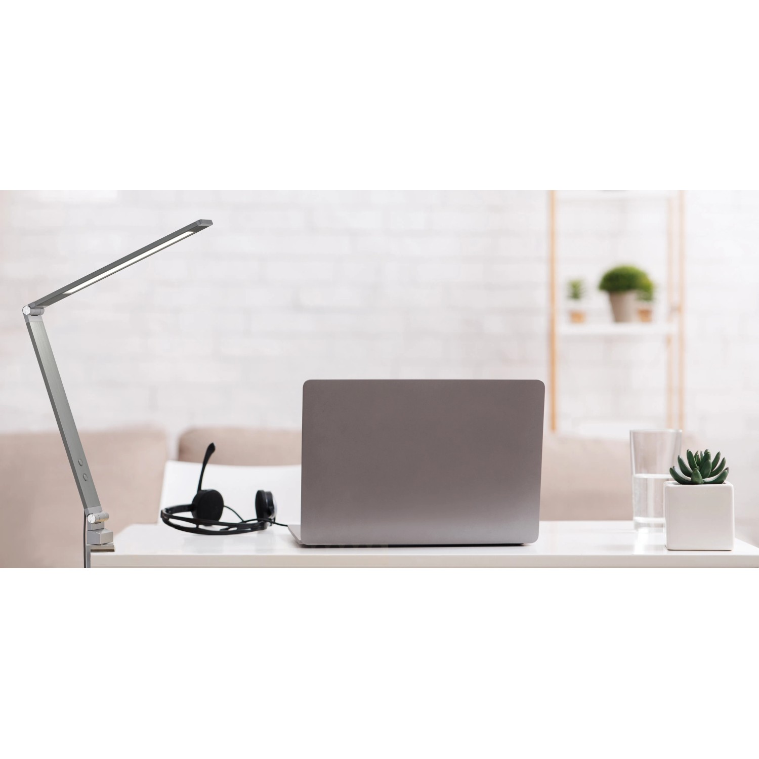Graue Fischer & Honsel LED-Klemmleuchte Geri am Schreibtisch mit Laptop und Headset.