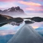Komar Vlies Fototapete Glowing Vestrahorn: Berglandschaft mit Wasserreflexionen und rosa Himmel.