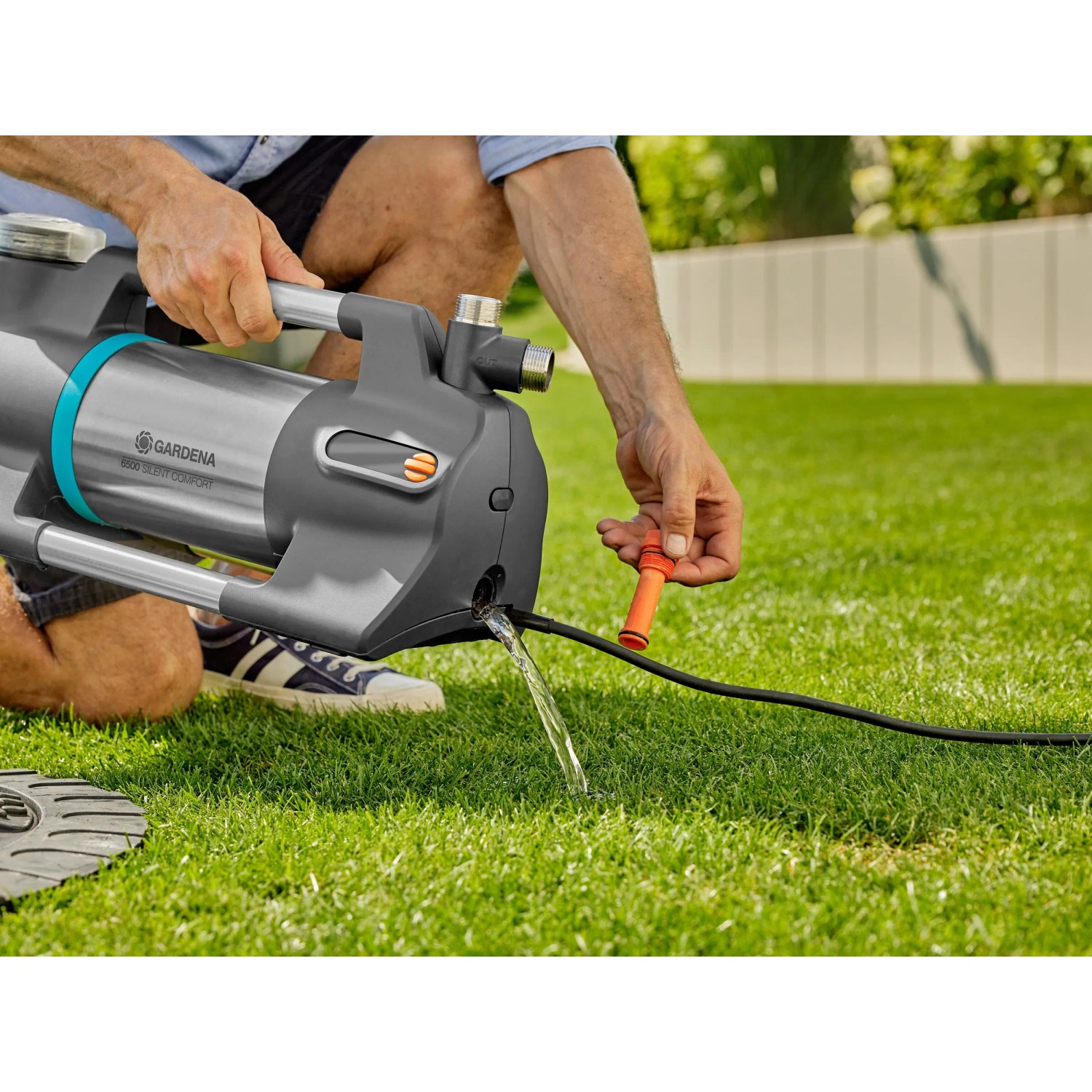 Gardena Gartenpumpe 6500 SilentComfort in Nutzung: Wasser fließt aus der grauen Pumpe auf Rasen.