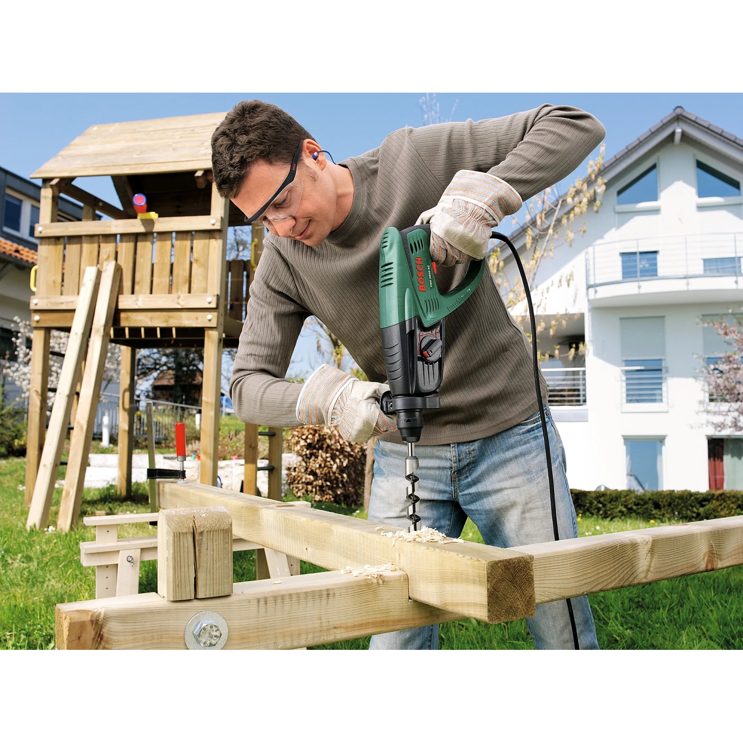 Mann bohrt mit dem Bosch Bohrhammer PBH 2800 RE in Holz. Der Bohrhammer ist grün und schwarz.