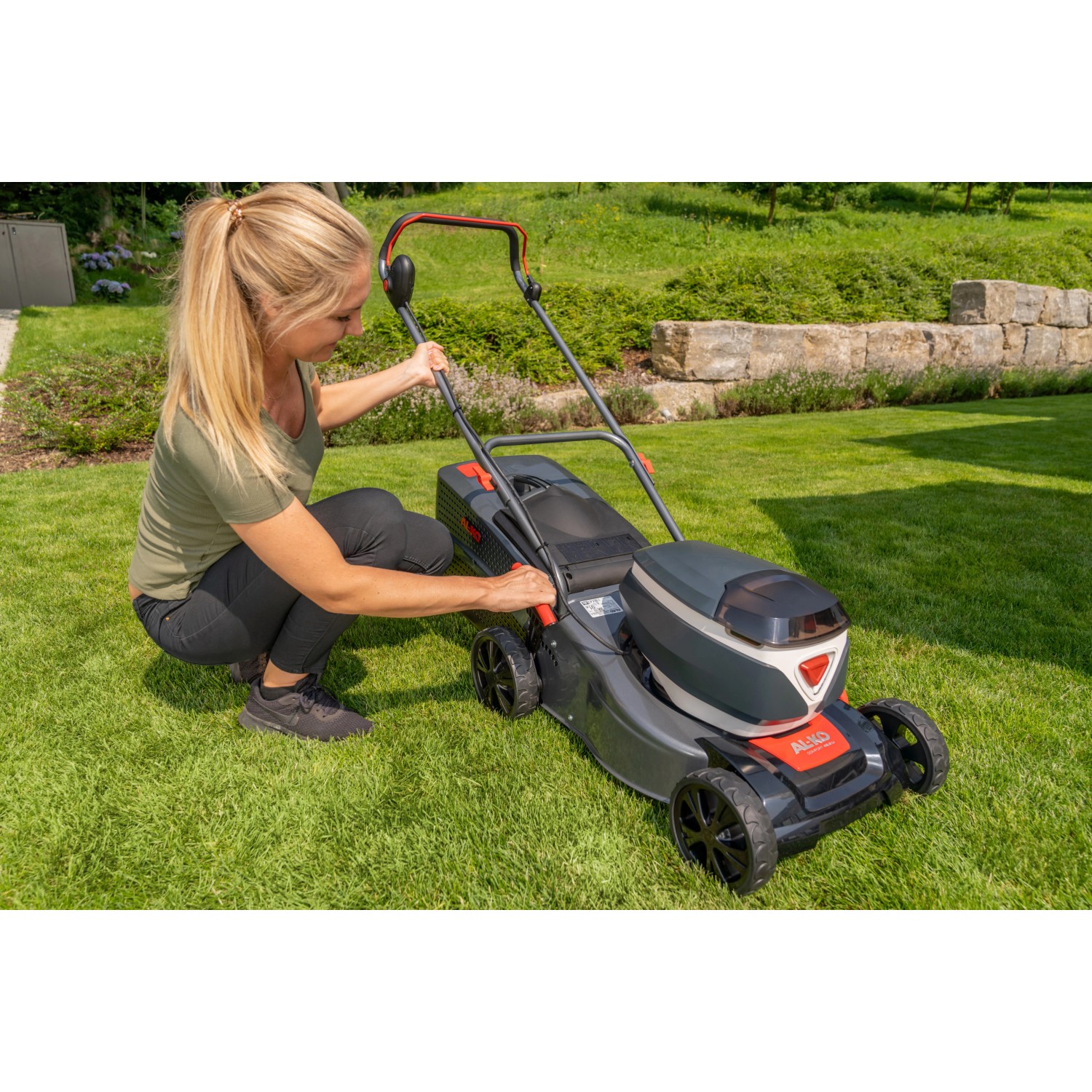 Al-Ko Akku-Rasenmäher 42.2 Li Comfort mit Frau beim Einstellen auf Rasenfläche.