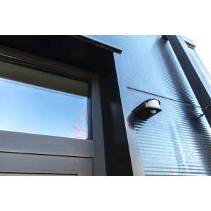 Schwarzer Lutec Bewegungsmelder Torus an einer Hauswand montiert.