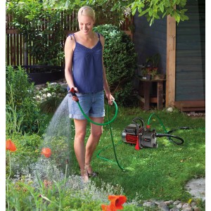 Frau bewässert Garten mit Einhell Gartenpumpen-Set GC-GP 6538, inklusive Schlauch.