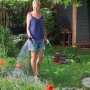 Frau bewässert Garten mit Einhell Gartenpumpen-Set GC-GP 6538, inklusive Schlauch.