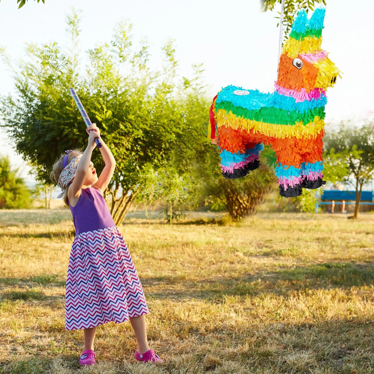Kind schlägt bunte Lama Pinata aus Papier auf Geburtstagsparty. Dekorative Figur für Partyspiel mit Süßigkeiten.