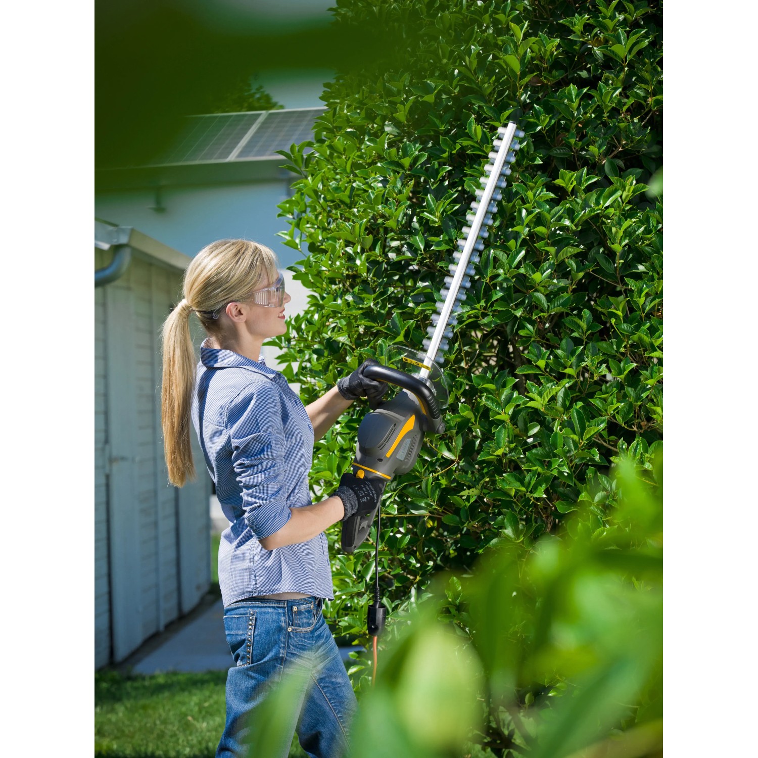 Frau schneidet Hecke mit Stiga Elektro-Heckenschere HT 106c. Leistungsstark und einfach zu bedienen.