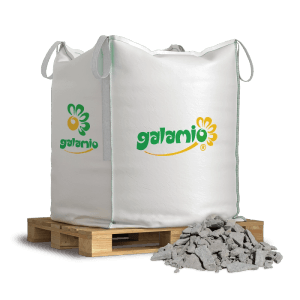 Weißer Galamio Frostschutzschotter 0-32 mm im 500kg BigBag auf Palette mit Schotterhaufen. Vielseitiges Baumaterial.