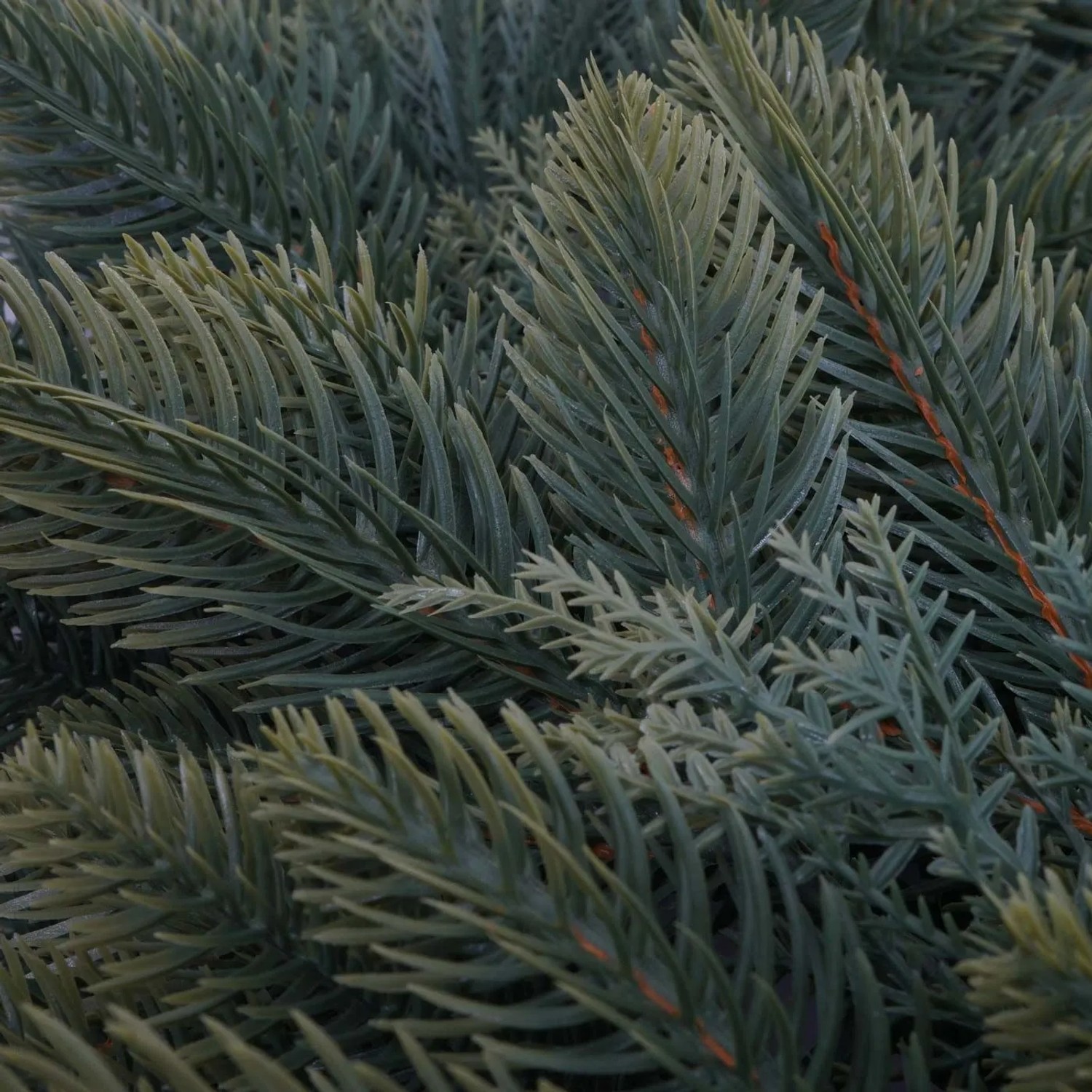 Nahaufnahme eines künstlichen Tannenkranzes aus Polyethylen mit grünen, detailreichen Nadeln. Ideal für Weihnachtsdekoration.