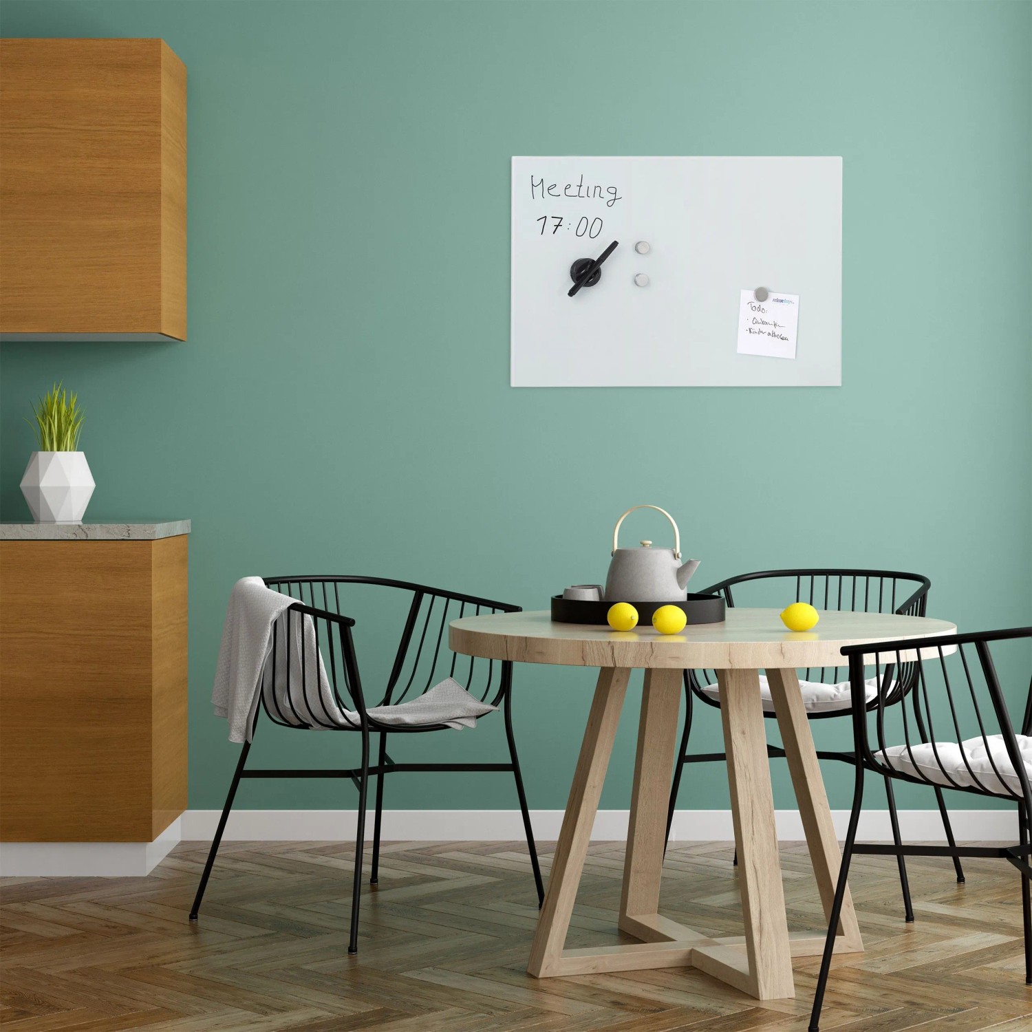 Weißes Relaxdays Glas Magnetboard (60x40 cm) im Büro über einem Tisch mit Teekanne und Zitronen.