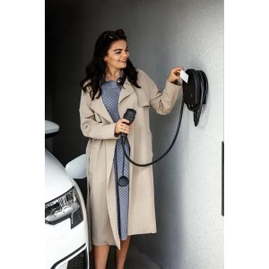 Frau lädt E-Auto mit Alphatec Wallbox Mini 11 kW. Kompakte Ladestation mit Kabel und Schlüssel.